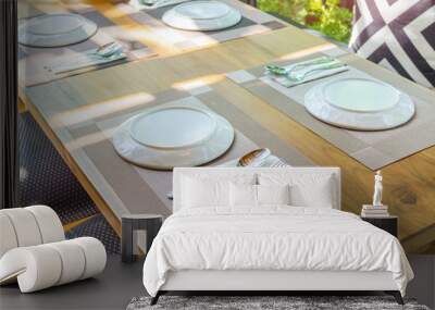 White plate with spoon and fork on the plate mat on wooden table Wall mural