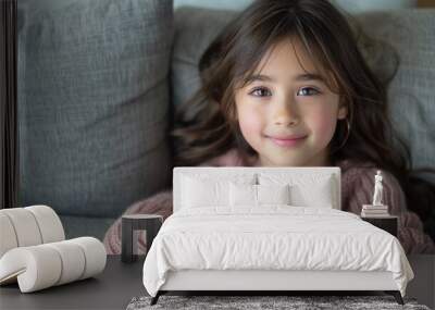 A cheerful girl enjoys her time at home, resting comfortably on a soft sofa Wall mural