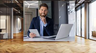 Confident businessman with laptop and tablet in modern office Wall mural