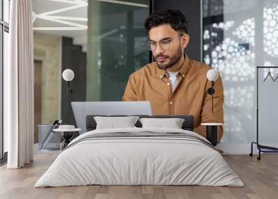 Focused professional working on a laptop in a modern office environment Wall mural