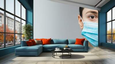 Woman with brown hair and a medical mask for protection again influenza. Copy space for your text. Woman with arms outstretched forward Wall mural