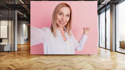 Photo of young beautiful smiling cheerful positive girl demonstrate take selfie isolated on pink color background Wall mural