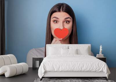 Portrait of adorable sweet lady hold small paper red card heart symbol cover mouth look camera on blue background Wall mural