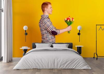 Profile side photo of young handsome man hold flower bouquet date isolated over yellow color background Wall mural