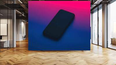 Smartphone lying on gradient blue and pink background Wall mural