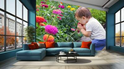 Cute little baby boy enjoying smelling flower with closed eyes. Agritourism. Slow living concept.  Summer countryside lifestyle Wall mural