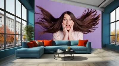 Surprised happy beautiful woman wind blow hairstyle open mouth on purple background Wall mural