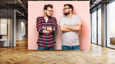 Two men thoughtfully pondering a decision while standing against a neutral backdrop Wall mural