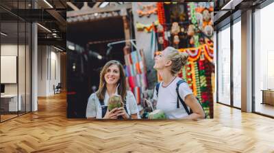 Two young happy women with coconuts at traditional bazaar in Dubai, UAE Wall mural