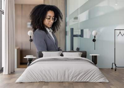 Young african american business woman enters office through electronic key, puts mobile phone to scan glass door lock Wall mural