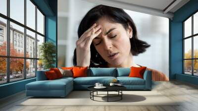 Young woman experiencing a headache, holding her forehead in discomfort Wall mural