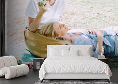 Young women with healthy food relaxing at summer picnic Wall mural