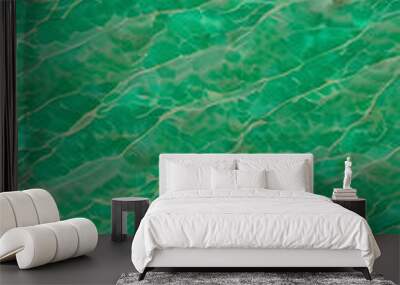 An abstract pattern of green waves resembling water surface, with a textured appearance a vibrant green color with a marbled effect, resembling jade. The light creates movement in the design. Wall mural