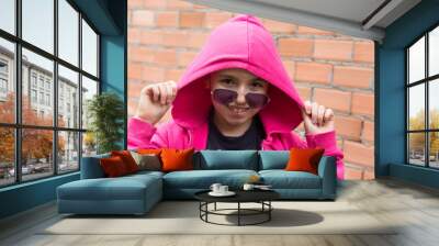 portrait of hipster girl with hoodie and sunglasses with brick wall background Wall mural