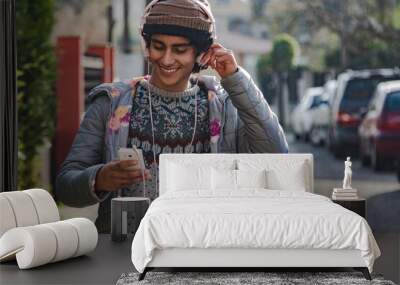 young latin hispanic man with headphones and phone on the street Wall mural