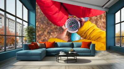 Girls Toddler holding compass in the hands. Children exploring nature in the forest on warm autumn day Kids learning how to use compass. Outdoor recreation and awesome adventures with children in fall Wall mural