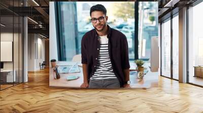 I am proud of what I do. Cropped portrait of a handsome young businessman wearing spectacles and leaning on his desk while working alone in his office. Wall mural