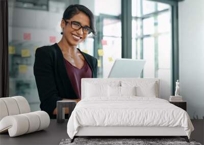 Its been a busy but successful day. Shot of an attractive young businesswoman standing alone in the office and using a digital tablet. Wall mural