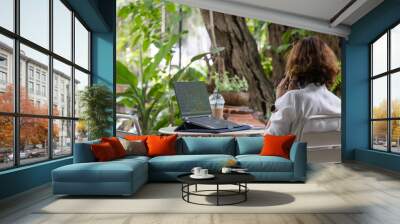 woman using a business phone And turn on the laptop to work Under the big tree Wall mural