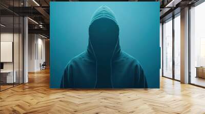 A hooded person is standing in front of a blue background Wall mural