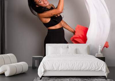 Brunette woman in black clothes doing gymnastic movements with white and orange cloths Wall mural