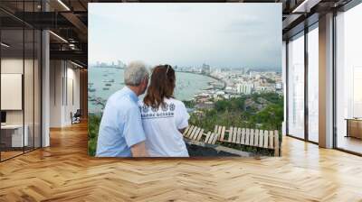 Couple sitting and looking at the landscape of the beautiful bay and city Landscape with beautiful cloudy sky, sea. Wall mural