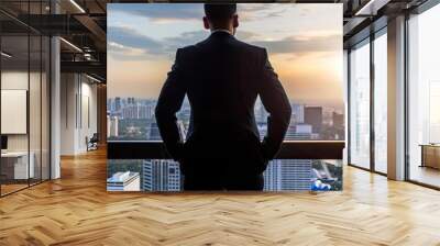 A businessman gazes out at a breathtaking city skyline during sunset, contemplating future opportunities and growth. Wall mural