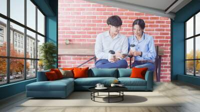 Asian young woman and young man are enjoy sitting at coffee shop, Asian young woman and young man hold with cup of coffee, Asian young woman looking telephone young man at coffee shop Wall mural