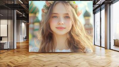 A young girl with a floral crown and soft smile, standing in front of a vibrant historic backdrop under clear blue skies. Wall mural