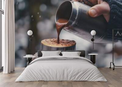 A close-up of a hand pouring a cup of hot chocolate from a thermos Wall mural