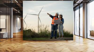 two engineers are standing in front of a wind turbine, pointing at a piece of paper. Scene is informative and professional, as the women are likely discussing the design  Wall mural