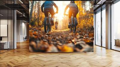 Cyclists enjoy an autumn ride on a leaf-covered forest trail, basking in the warm glow of the setting sun, surrounded by nature's vibrant colors. Wall mural