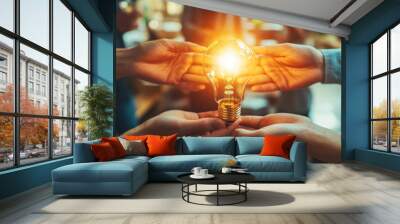 Hands holding a glowing light bulb, symbolizing ideas, collaboration, and innovation in a creative environment. Wall mural