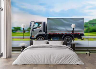 Side view of a small white truck swiftly driving on a country road, illustrating dynamic motion against a lush green rural landscape Wall mural