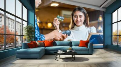 Asian customer man paying with credit card via contactless nfs technology to Asian Barista of Small business owner at the table in coffee shop, Small business owner and startup in coffee shop concept Wall mural