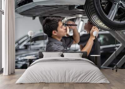 Asian mechanic Checking and torch tire in maintainance service center which is a part of showroom, technician or engineer professional work for customer, car repair concept Wall mural