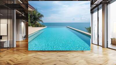 A serene infinity pool overlooking a vast ocean, surrounded by lush greenery and bright sky, perfect for relaxation and luxury. Wall mural