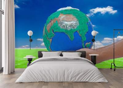 man his hands holding globe made from clay on green grass and bl Wall mural