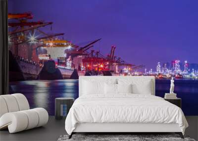 Panorama image of Container cargo ship with ports crane bridge loading dock to terminal in harbor against refinery industrial at twilight Wall mural