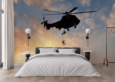 silhouette of military commando helicopter drops between are in flight for operation battle combat in sunset Wall mural