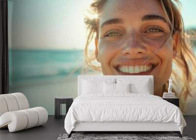 A realistic close-up photo of a woman with a radiant smile on the beach, her face glowing under the sun, with a hint of the ocean in the background Wall mural