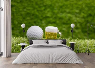 Golf ball and glass of beer on green grass background Wall mural