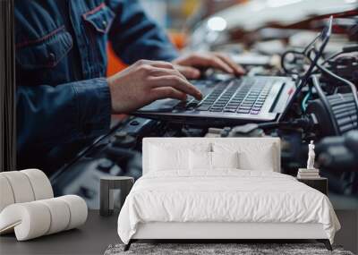 Mechanic using a laptop for car diagnostics, Hand of mechanic in blue uniform on laptop over car engine, soft blue glove, focused task, blurred workshop setting, symbolizes technical analysis. Wall mural