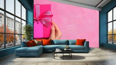 Creating a personalized touch two hands arranging a custom tag on a beautiful gift box displayed on a pink background Wall mural