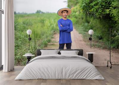 Full body of Asian farmer man standing and cross hands looking sky at green farm Wall mural