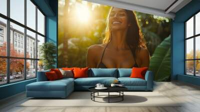 Smiling woman in black bikini enjoying sunlight in lush tropical foliage. Female embracing serene and joyful moment in nature  Wall mural