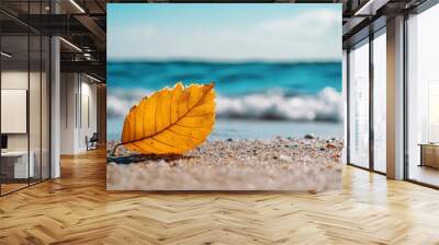 Sunny day at the beach with a yellow autumn leaf in focus against blurred waves providing a serene backdrop in a copy space image Wall mural