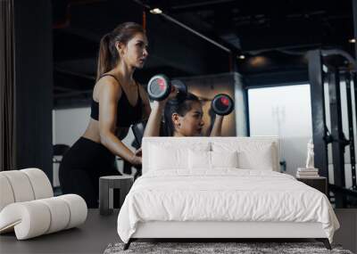 Sporty girl doing weight exercises with the help of her personal trainer at the gym. Wall mural