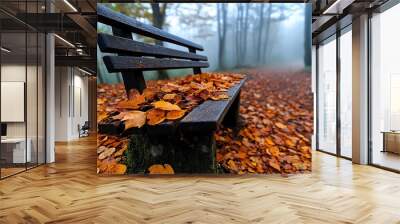 An old wooden bench, covered in fallen leaves, sitting quietly in a secluded part of the forest surrounded by mist Wall mural