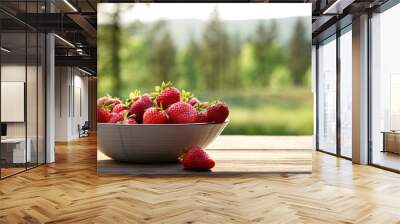 Bowl juicy pile of red strawberries on wooden table on blur forest background with copy space Wall mural